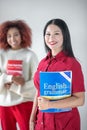 Asian dark-haired woman holding English grammar book Royalty Free Stock Photo