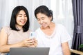 Asian daughter with old mother using mobile phone and laptop sharing technology together Royalty Free Stock Photo