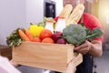 Asian deliver man in red uniform handling wooden crate box of food, fruit, vegetable give to female costumer. Postman and express Royalty Free Stock Photo