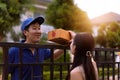 Asian delivery man in blue shirt sending parcel box to home while young woman receiving a package in front of custoomer Royalty Free Stock Photo