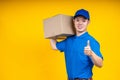Asian delivery man in blue t-shirt carrying parcel box and show thumb up Royalty Free Stock Photo