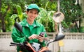 Asian delivery man check and accept part time job via application on smartphone device while wearing green jacket uniform with cap