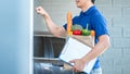 Asian delivery man holding grocery bag of food, fruit, vegetable and  invoice clipboard during knocking Royalty Free Stock Photo