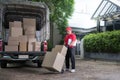 Asian delivery man in red uniform delivering parcel boxes to woman recipient at home Royalty Free Stock Photo