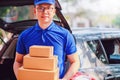 Asian delivery man wearing a blue shirt checking and carrying paper parcel boxes in the back of the delivery car with copy space. Royalty Free Stock Photo