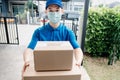 Asian Delivery man wearing mask send a package carton on front receiver shipping deliver social distancing Royalty Free Stock Photo