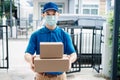 Asian Delivery man wearing mask send a package carton on front receiver shipping deliver social distancing Royalty Free Stock Photo
