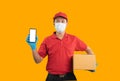 Asian delivery man worker showing mobile phone on white screen wearing surgical mask, medical gloves in red uniform isolated on Royalty Free Stock Photo