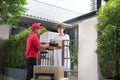 Asian delivery man in red uniform delivering parcel boxes to woman recipient at home Royalty Free Stock Photo