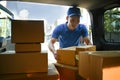 Asian delivery men unloading cardboard boxes from cargo van. Delivery service, delivery home and shipping concept Royalty Free Stock Photo