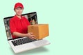 Asian delivery woman in red shirt with blur warehouse background, holding goods order in package parcel out from laptop computer Royalty Free Stock Photo