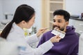 Asian dentist checking and selecting color of young bearded man teeth. Royalty Free Stock Photo