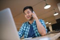 Asian designer using a laptop and talking on his cellphone Royalty Free Stock Photo