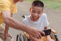 Asian Disabled child and adult on wheelchair in city park,They have fun with selfie by smart phone