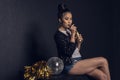 Asian disco girl with golden bottle, disco ball and pom-pom posing and looking at camera Royalty Free Stock Photo