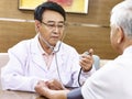 Asian doctor checking blood pressure of a senior patient Royalty Free Stock Photo