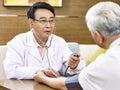 Asian doctor checking blood pressure of a senior patient Royalty Free Stock Photo