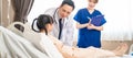 Asian doctor and nurse checking health of young patient girl in hospital recovery room. The sickness little kid feeling better lyi Royalty Free Stock Photo