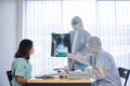 Asian doctor in personal protective equipment or ppe explain the x-ray film of covid-19 or coronavirus infection to patient Royalty Free Stock Photo