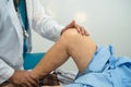Asian doctor physiotherapist examining, massaging and treatment knee and leg of senior patient in orthopedist medical clinic nurse