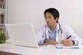 Asian Doctor and Stethoscope Write Experimental Results Report and Using Laptop Computer Royalty Free Stock Photo