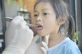 Asian doctor in surgical gown examining a little cute asian patient girl with  throat sick in office. Medicine and health care Royalty Free Stock Photo