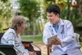 Asian doctor talking with elderly female patient on wheelchair Royalty Free Stock Photo