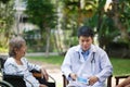 Asian doctor talking with elderly female patient on wheelchair Royalty Free Stock Photo