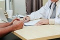 Asian doctor talking and taking notes with male patient consult Royalty Free Stock Photo