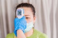 Asian doctor using infrared forehead thermometer gun checking of woman