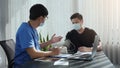 Asian doctor is using a patient`s blood pressure monitor at the time of his annual check-up and explains his blood pressure