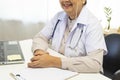 Asian doctor woman using a laptop computer and writing something on clipboard at hospital desk office. Royalty Free Stock Photo