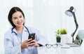 Doctor woman smiling using working with smart mobile phone Royalty Free Stock Photo