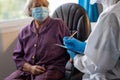 Asian doctors in the protective suits and masks are examining the aging female patient that is at risk for infection corona virus