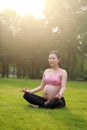 Asian Eastern Chinese happy beautiful pregnant woman do yoga sit in meditation in nature outdoor sit on green grass meadow park Royalty Free Stock Photo