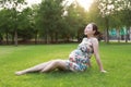 Asian Eastern Chinese happy beautiful pregnant woman in traditional chi-pao cheongsam sit on grass meadow sunset sunrise day free