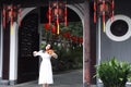 Asian Eastern Chinese young artist player woman play violin perform music garden nature outdoor ancient building red lantern