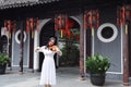 Asian Eastern Chinese young artist player woman play violin perform music garden nature outdoor ancient building red lantern