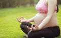Asian Eastern Chinese young pretty pregnant girl woman do yoga sit in meditation, do lotus gesture of yoga in outdoor nature sun Royalty Free Stock Photo