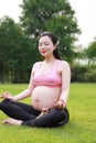Asian Eastern Chinese young pretty pregnant girl woman do yoga sit in meditation in nature outdoor sunset, keep healthy, mother Royalty Free Stock Photo