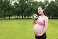 Asian Eastern Chinese young pretty pregnant girl woman mother one hand on belly one hand with bouquet expecting baby to born