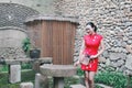 Asian Eastern oriental Chinese woman beauty in traditional ancient dress costume red cheongsam with fan in ancient yard town Royalty Free Stock Photo