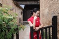 Asian Eastern oriental Chinese woman beauty in traditional ancient dress costume red cheongsam in ancient town garden fence Royalty Free Stock Photo