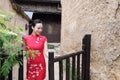 Asian Eastern oriental Chinese woman beauty in traditional ancient dress costume red cheongsam in ancient town garden fence