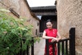 Asian Eastern oriental Chinese woman beauty in traditional ancient dress costume red cheongsam in ancient town garden fence Royalty Free Stock Photo