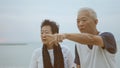 Asian senior elder couple holding hands looking sunset sea ocean together happy retirement life Royalty Free Stock Photo