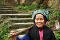 Asian elderly Chinese woman farmer peasant with hoe on shoulder.