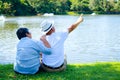 Asian elderly couple enjoying a good day sitting on the grass by the pool in the park. Royalty Free Stock Photo