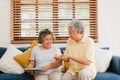 Asian elderly couple man holding cake celebrating wife`s birthday in living room at home. Japanese couple enjoy love moment Royalty Free Stock Photo