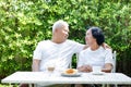 Asian elderly couple sitting in the morning drinking coffee and chatting in the front yard. Royalty Free Stock Photo